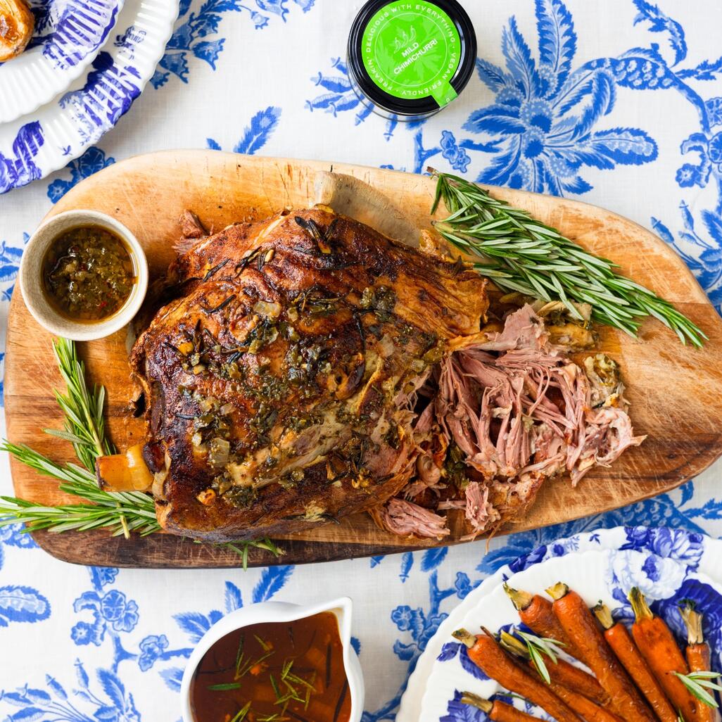 cooked meat on wooden board with chimichurri sauce on side 