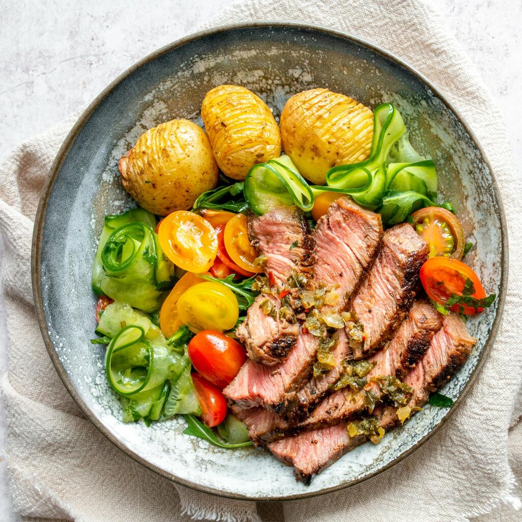 cooked meat on with chimichurri sauce on side 