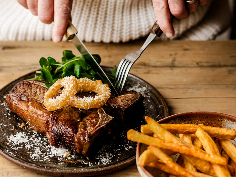 beef t bone steak with homemade chips and onion rings cooked