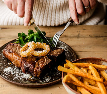 beef t bone steak with homemade chips and onion rings cooked