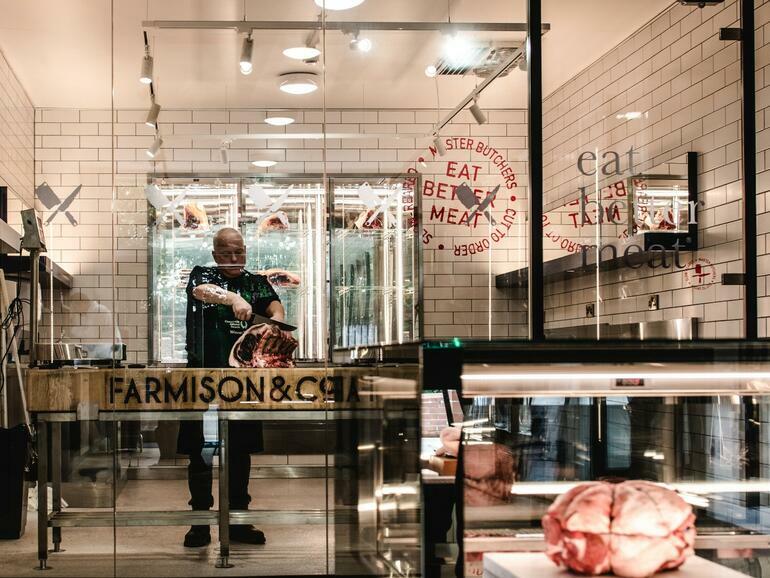 inside Farmison’s physical butcher’s shop, the Cut, with a butcher standing cutting meat